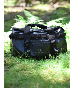 black tarpaulin duffle bag placed in green grass
